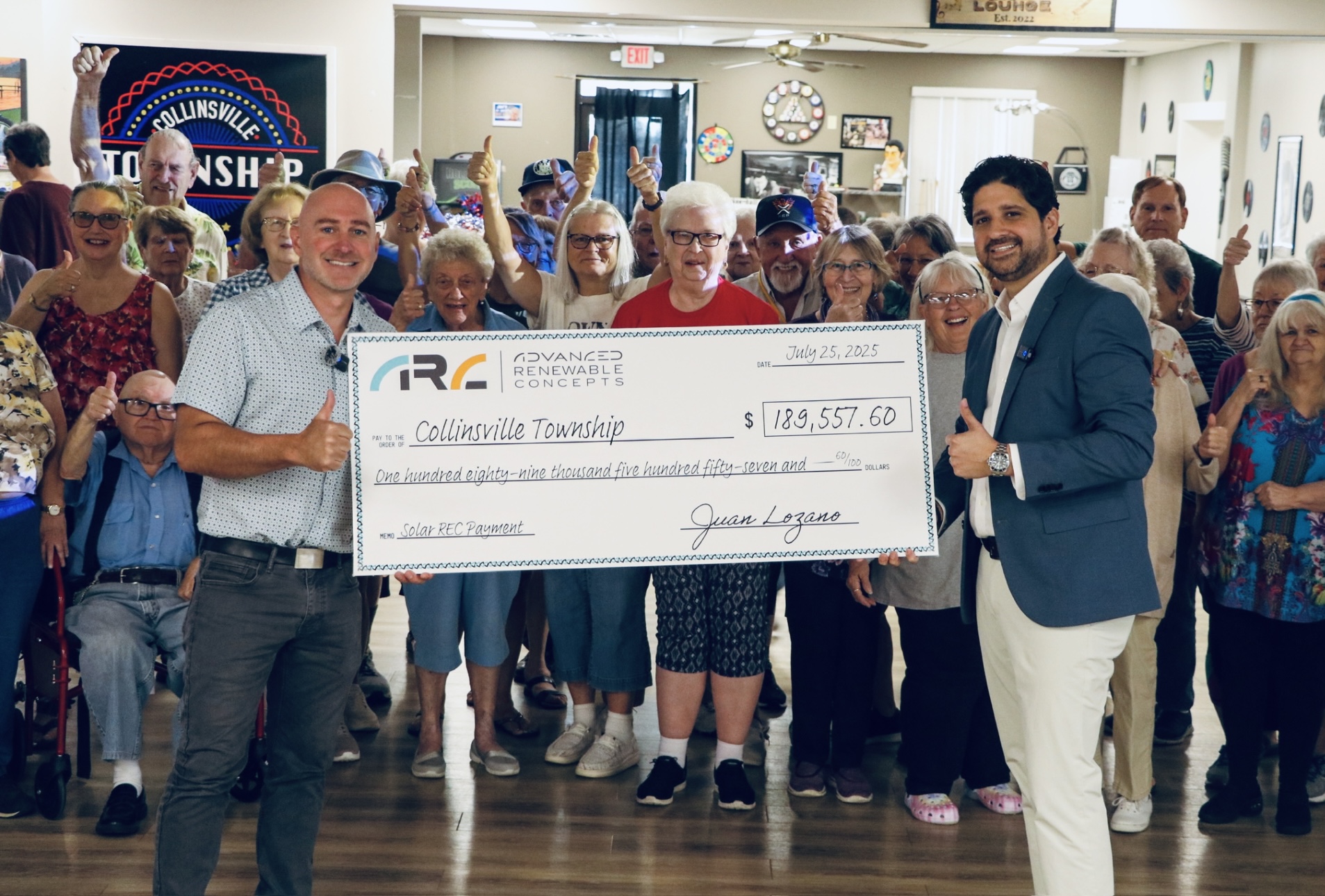 Group picture of the Township staff in front of community people holding up a giant check